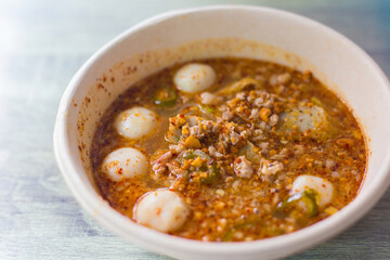 Closeup Spicy Tom Yum pork noodles with soup which contains fish balls, chilly pasted and lime juice. This noodles is a hot spicy and sour taste in Thai food style.