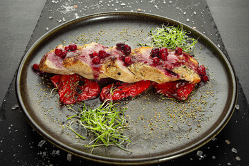 Baked pork meat glazed with cranberry sauce placed on grilled bell pepper, served with green sprouts