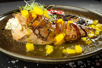 Grilled chicken breast with pineapple and grilled vegetables. A dish of author's cuisine on a dark background.