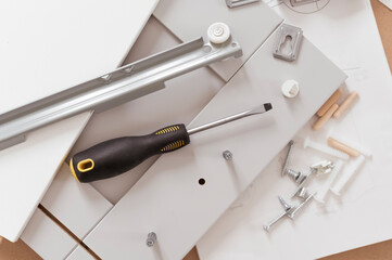 individual project kitchen furniture concept. Parts and tools for assembling furniture on the floor. Top view screws and screwdriver with nobody