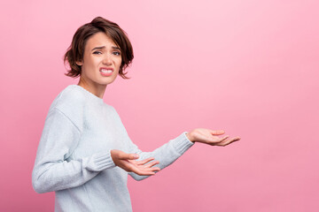 Photo of unhappy young brunette lady show empty space wear blue sweater isolated on pink color background