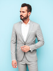 Portrait of handsome confident stylish hipster lambersexual model.Sexy modern man dressed in elegant suit. Fashion male posing in studio near blue wall