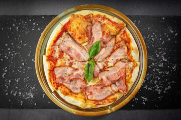 Italian bacon pizza with cheese sauce and crispy pepper with roasted spice mix, wooden dish plate on a stone table top.