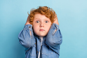 Photo of scared nervous guilty ginger kid touch head speechless wear jeans jacket isolated blue color background - obrazy, fototapety, plakaty