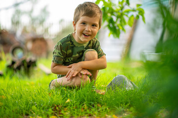 a boy in a green T-shirt sitting on the grass