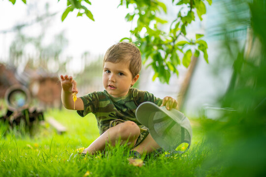a boy in a green T-shirt sitting on the grass