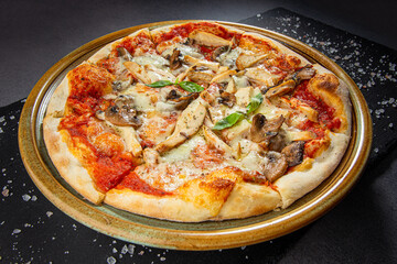 Pizza with chicken and mushroom. wooden dish plate on a stone table top.