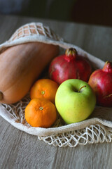 Crochet bag filled with butternut squash, pomegranates, apples and tangeriens. Selective focus.