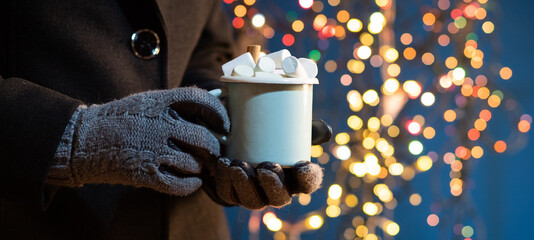 woman holding mug with mulled wine or hot chocolate at christmas market