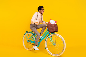 Full length body size photo man riding bike with basket having present isolated vivid yellow color...
