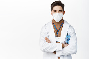 Coronavirus. Doctor in medical face mask and hospital uniform, cross arms, standing confident over white background