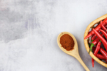 Ground red hot peppers in a wooden spoon. Hot chili peppers in a straw basket. Banner about spices and national cuisine. Culinary template for adding text.
