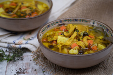 Vegan  carrot and potato soup made with seitan and vegetable stock. White wooden table, burlap cloth