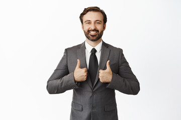 Business people. Handsome corporate man in suit, smiling and showing thumbs up, praise work, good job, saying yes, standing over white background