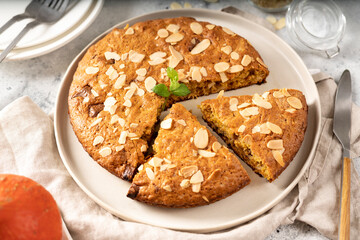 Homemade pumpkin pie with almonds and chocolate in a white plate on a light table close-up