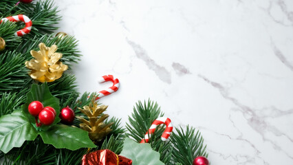 Green pine tree leaves, red christmas decorations and candy canes on white marble background, christmas decorations in bright red color. Simple and creative christmas concept.