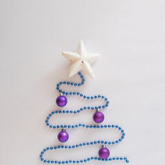 Christmas tree flat lay design on a white background.Made of pearls,baubles and star for New Year celebrate decoration.Winter holidays aesthetic concept