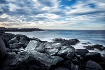 Dramatic seascape with stones on the shore. Long exposure. Blurred water. Coast of the Atlantic Ocean. USA. Maine.