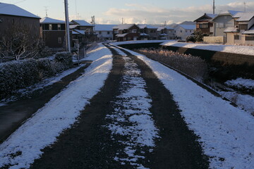 Fototapeta na wymiar 川沿いの道の雪景色