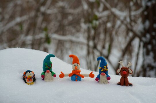 A snowman, a deer, a penguin and two dwarfs in a snowy forest.