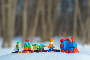 Christmas train made of plasticine in the forest on the background of snow.