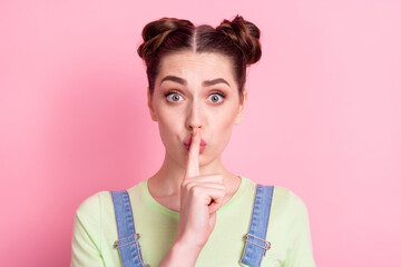 Fototapeta premium Photo portrait girl in overall keeping secret finger near lips isolated pastel pink color background