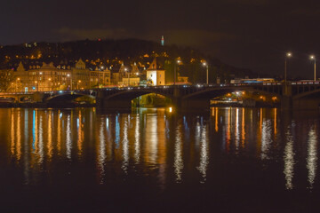 Night city landscape with river and bridge, street lights are reflected in the water surface