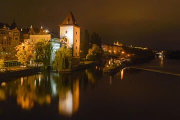 Fototapeta premium Night city with river and tower, street lights are reflected in the water surface