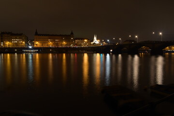 Fototapeta na wymiar Night city with river and church, street lights reflected in water surface, beautiful landscape