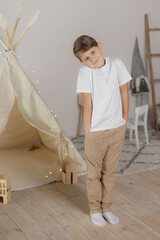 Minimalistic studio photo of eight old caucasian boy wearing in white t-shirt and beige pants for creating mockups for presentation graphic tees and pattern design