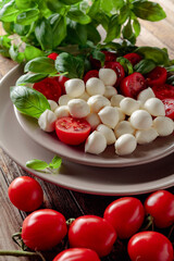 Caprese salad with tomato, mini mozzarella and basil on a old wooden table.