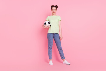 Fototapeta premium Photo of confident girl hold soccer ball look camera wear green t-shirt jeans footwear isolated on pink background