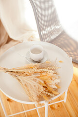 a white cup and a bouquet of dry flowers on the coffee table in the living room