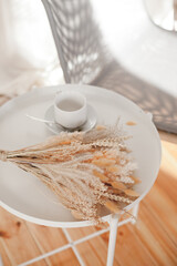 a white cup and a bouquet of dry flowers on the coffee table in the living room