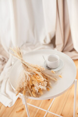 a white cup and a bouquet of dry flowers on the coffee table in the living room