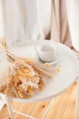 a white cup and a bouquet of dry flowers on the coffee table in the living room
