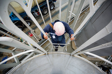 The male worker down the ladder is for inspection stainless steel tank. © chitsanupong