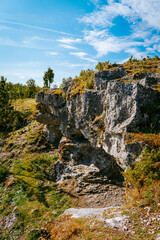 Uugu bluff or cliff on the Muhu Island in Estonia, located by the Baltic sea and near the island of Saaremaa. Beautiful sunny day with blue sky, white clouds, forest and stone cliffs by the seaside.