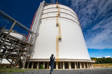 Male workers works permit industry visual inspection of the big white tanks for gas propane