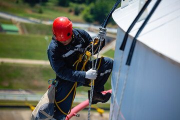 Obraz premium Focus male worker down height tank roof rope access safety inspection of thickness storage tank gas