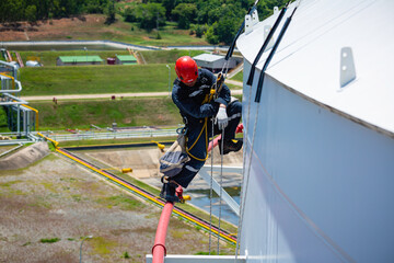 Focus male worker down height tank roof rope access safety inspection of thickness storage tank gas