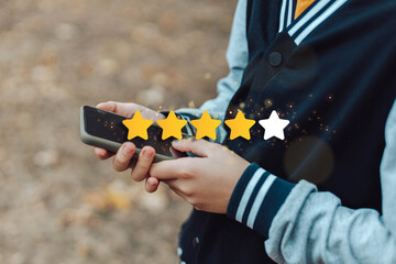 Customer Experience Concept. Child hands uses smartphone with icon one star symbol to increase...