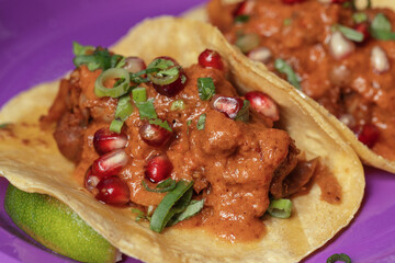 Traditional Mexican tacos with meat and vegetables in purple paper plates served for takeaway. Mexican food background.