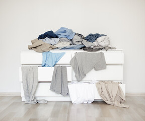 housework and routine concept - chest of drawers with pile of dirty laundry