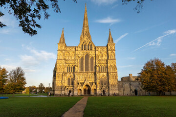 Fototapeta na wymiar Salisbury, Wiltshire, England, UK. 2021. Salisbury Cathedral, west front seen with glow of the setting sun and a blue sky.
