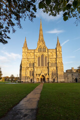 Salisbury, Wiltshire, England, UK. 2021. Salisbury Cathedral, west front seen with glow of the setting sun and a blue sky.