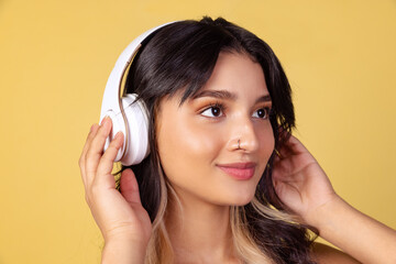 Close-up portrait of young beuatiful girl, student listening to music isolated on yellow studio backgroud.