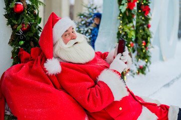 Santa claus using the phone outdoors. Merry Christmas.
