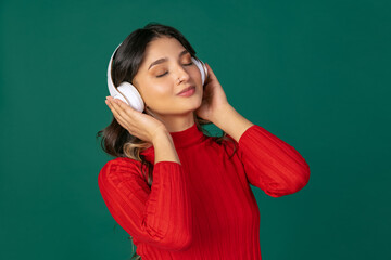 Close-up portrait of young beuatiful girl, student in bright red sweater isolated on green studio...