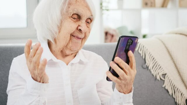 Elderly woman making video call with smartphone and smiling during converstation